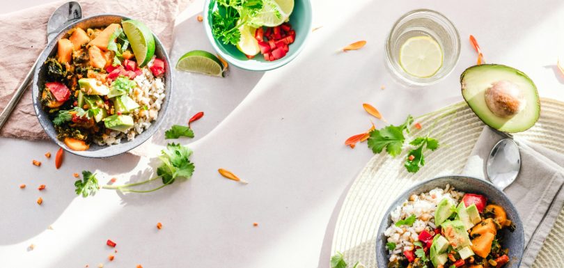 Gut-friendly foods in rice bowls with avocado, vegetables, lime, and herbs