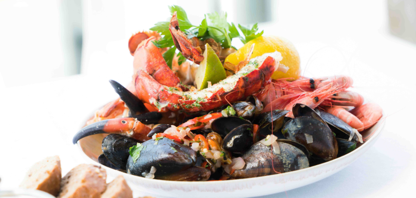 Seafood platter with lobster, mussels, shrimp, crab claws, lemon, and herbs