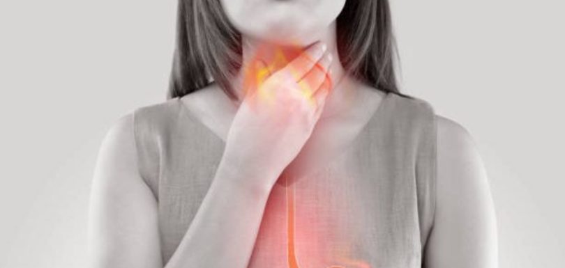 Woman holding her throat with an illustration of acid reflux in the esophagus