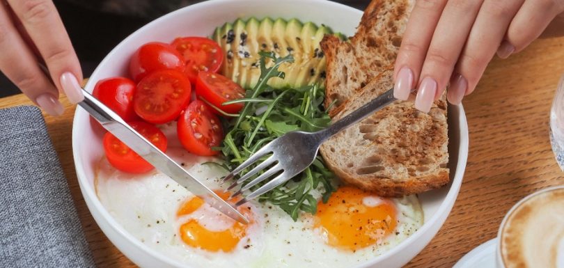 Blood sugar-balanced breakfast with eggs, avocado, tomatoes, arugula, and whole-grain toast
