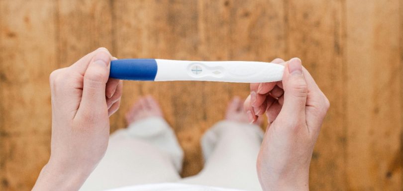 Person holding a positive pregnancy test while exploring blood sugar and fertility