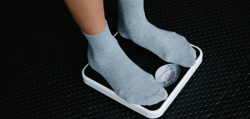 Person standing on a scale while working toward sustainable weight loss