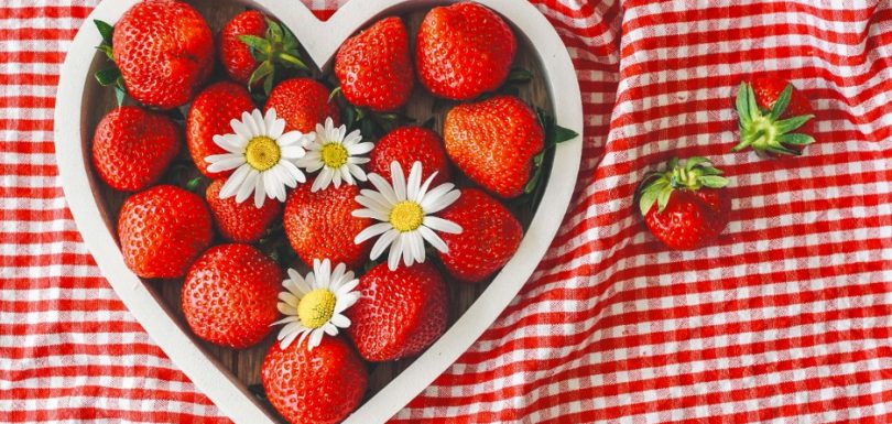 Fresh strawberries arranged in a heart-shaped bowl