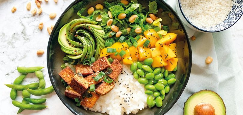 Balanced meal with tofu, rice, edamame, avocado, mango, greens, and nuts