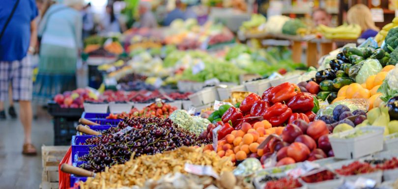 Fresh fruits and vegetables displayed at a busy farmers market