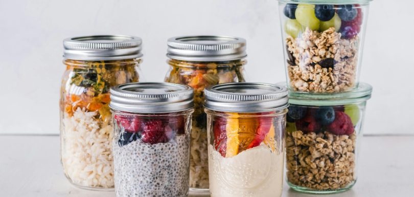 Healthy meal prep jars with chia pudding, berries, granola, rice, and vegetables