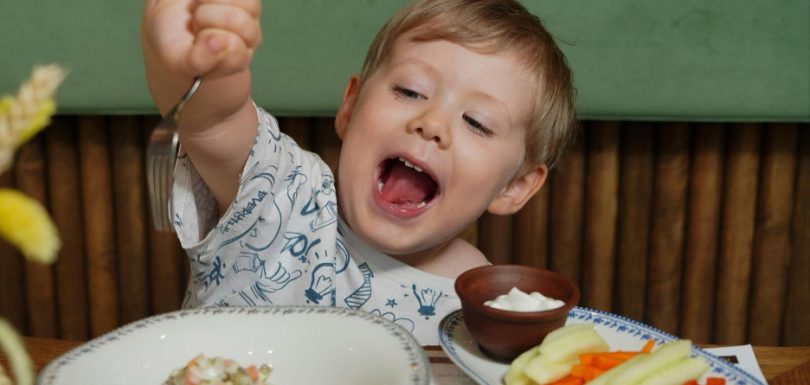 Young child eating vegetables during a family meal