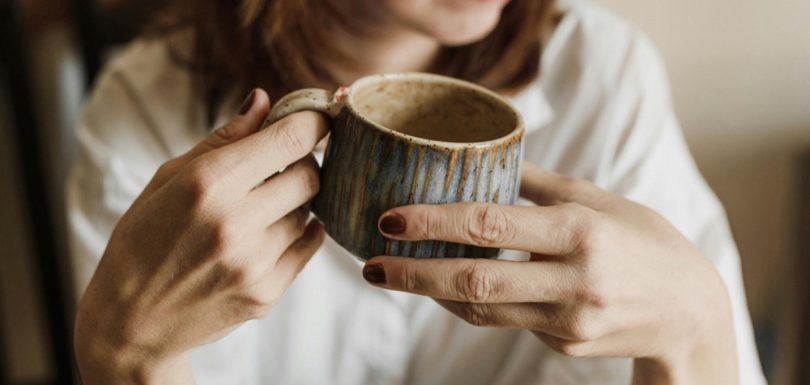 Woman holding a warm drink as part of a relaxed wellness routine